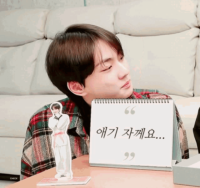 a young man sitting in front of a calendar with korean writing