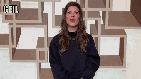 a woman wearing a black sweater stands in front of a wall with the word gail on it
