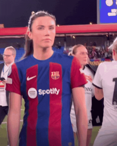 a woman wearing a spotify jersey stands on a soccer field