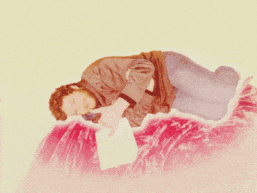 a man with a beard is laying on a red couch talking on a cell phone