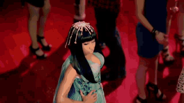 a woman in a blue dress is standing on a red carpet in front of a crowd of people