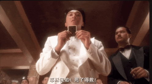 a man in a tuxedo holds up a playing card with chinese writing
