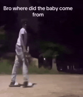 a man is walking down a street at night holding a baby .