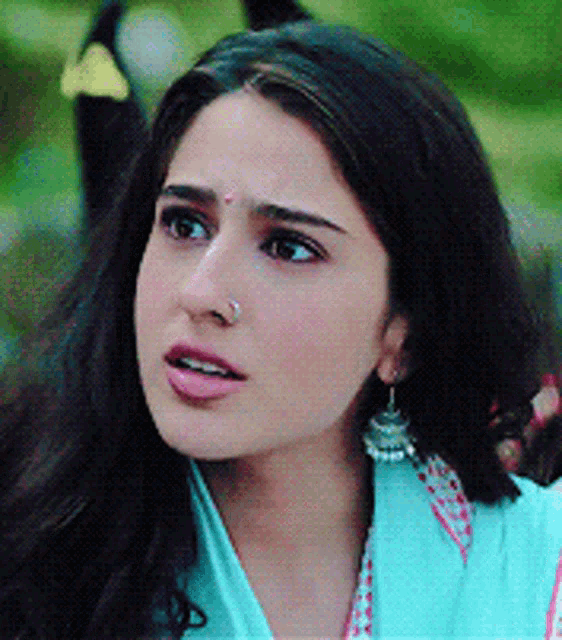a woman with a nose ring and earrings looks at the camera