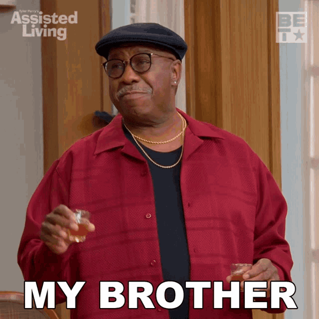 a man in a red shirt is holding a glass of whiskey and says my brother
