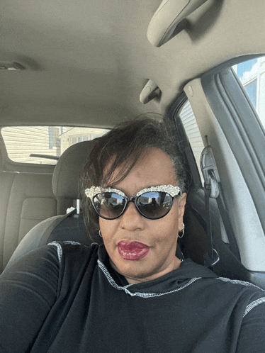 a woman wearing sunglasses and a black shirt is sitting in a car