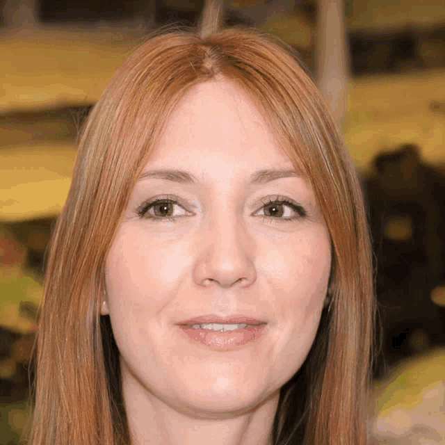a woman with long red hair and brown eyes smiles for the camera