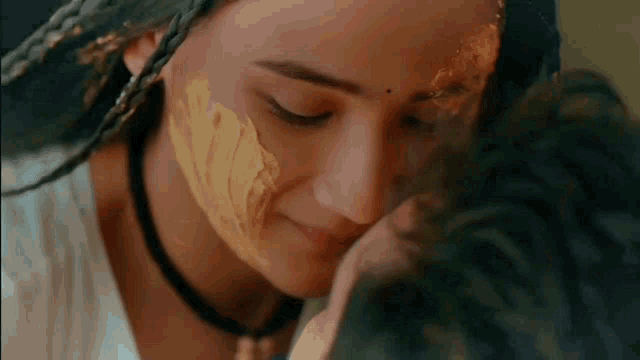 a woman with yellow paint on her face is kissing a man on the forehead .