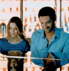 a man and a woman are sitting at a bar looking at something