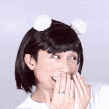 a man wearing a wig and a headband with pom poms on it is laughing .