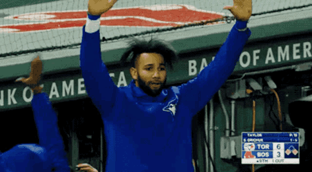 a blue jays player stands in front of a scoreboard