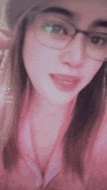 a close up of a woman wearing glasses and a pink shirt with a tiktok logo