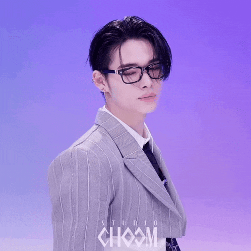 a young man wearing glasses and a suit has the word choom on his chest