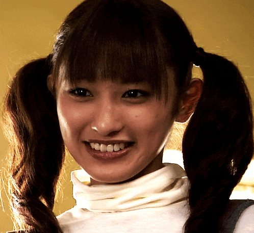 a woman with pigtails and a white turtleneck is smiling