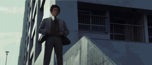 a man in a suit and tie is standing on a set of stairs in front of a building
