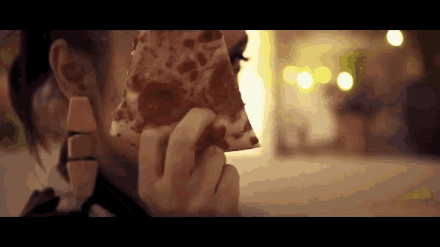 a close up of a woman eating a slice of pepperoni pizza