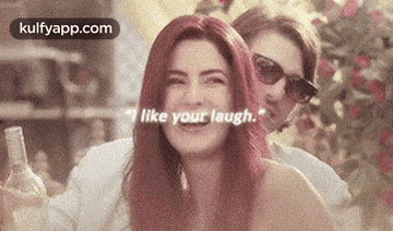 a woman with red hair is laughing with a man behind her .