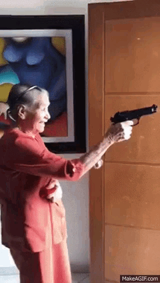 an elderly woman in a red dress is holding a gun
