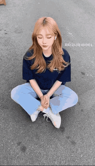 a girl is sitting on the ground with her eyes closed and the letters l on the bottom right