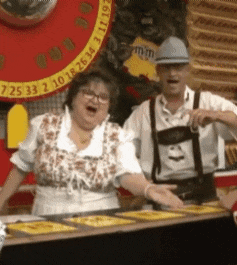 a man and a woman are standing in front of a roulette wheel with the numbers 7 25 33 2 10 18 26 34 on it