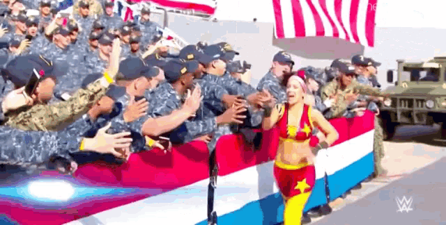 a woman in a bikini stands in front of a crowd of soldiers .