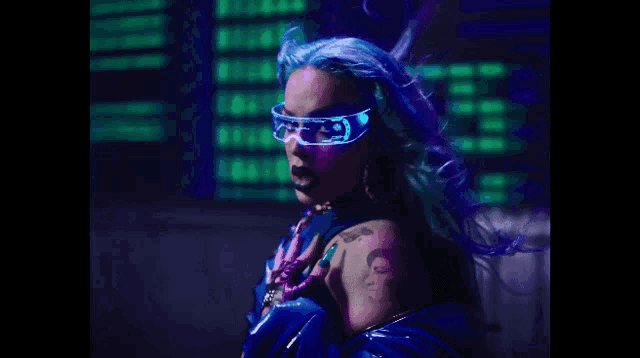 a woman with blue hair and futuristic glasses is standing in front of a building at night .