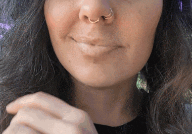 a close up of a woman 's face with a gold nose ring