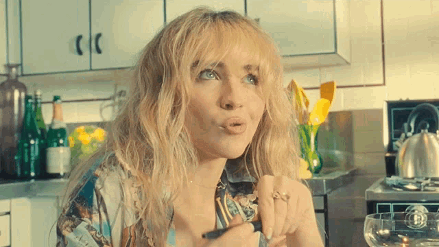 a woman with blonde hair and a ring on her finger looks surprised