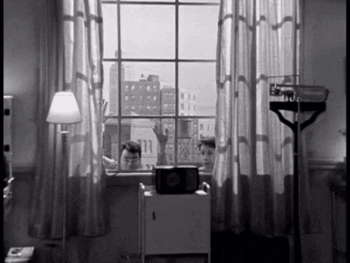 a black and white photo of two men looking out a window with the number 11 visible