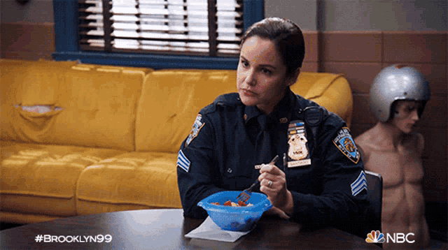 a woman in a police uniform sits at a table with a bowl of food
