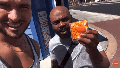 a man holding a piece of pizza next to another man with a sign that says 7 hours 7 days