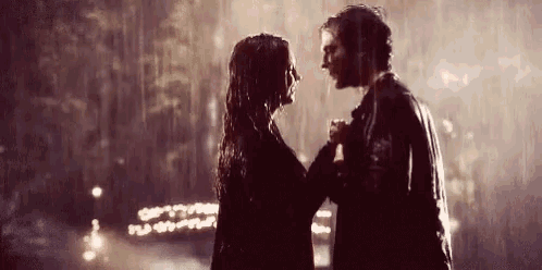 a man and a woman are dancing in the rain and looking into each other 's eyes .