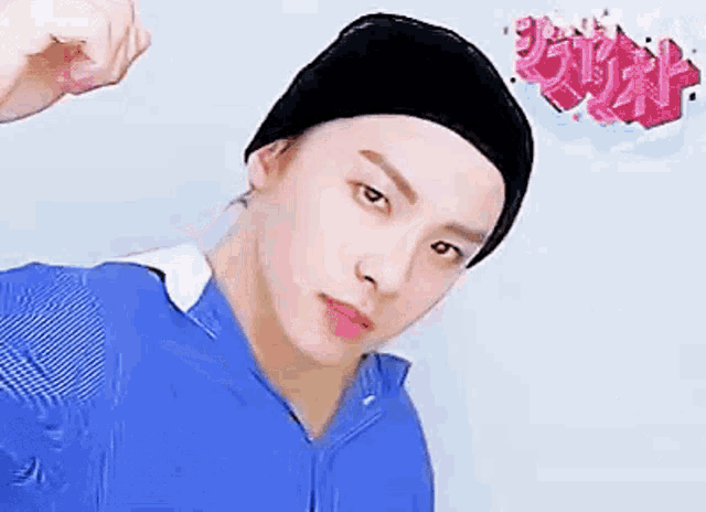 a young man wearing a beanie and a blue shirt is making a funny face .