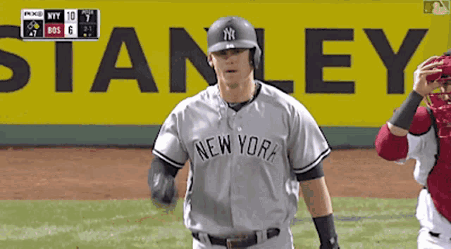 a baseball player for the new york yankees stands in front of a stanley ad