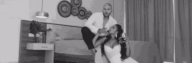 a black and white photo of a man and a woman sitting on a couch .