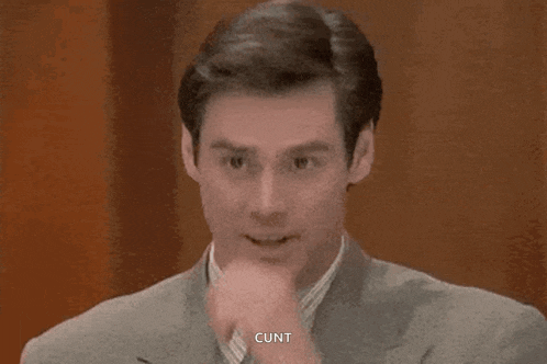 a man in a suit is holding his hand to his mouth and saying , `` cunt '' .