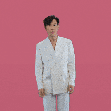 a man in a white suit is making a funny face with his hands on his ears