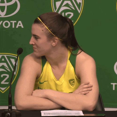 a woman sits at a table with her arms crossed in front of a green toyota sign