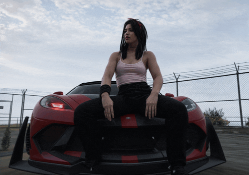 a woman with dreadlocks sits on the front of a red car