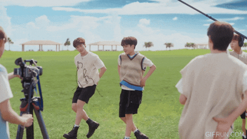 a group of young men are standing in a grassy field with gifrun.com at the bottom of the screen