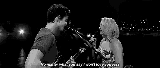 a man and a woman are singing into microphones on a stage .