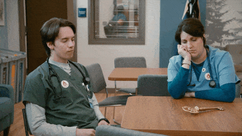 a man with a stethoscope around his neck sits next to a nurse
