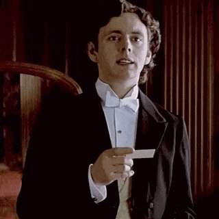 a man in a tuxedo and bow tie is holding a piece of paper in his hand