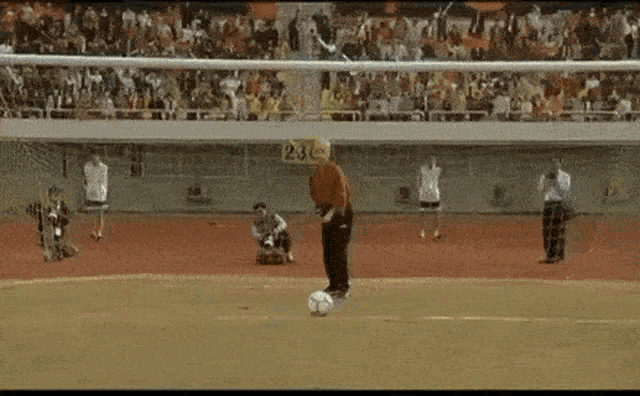 a man is kicking a soccer ball on a field with a yellow sign that says 23c