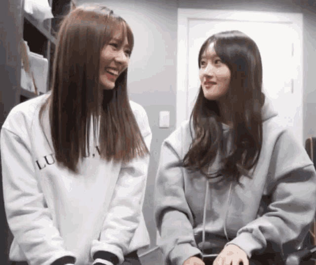 two girls wearing sweatshirts with the word lu on the front