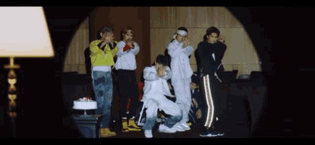 a group of people are dancing in a room with a cake