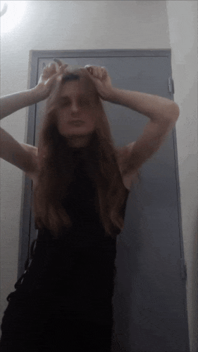 a woman in a black dress stands in front of a door