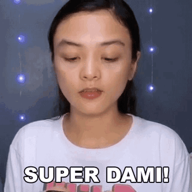 a woman in a white t-shirt is making a face and saying `` super dami ! ''
