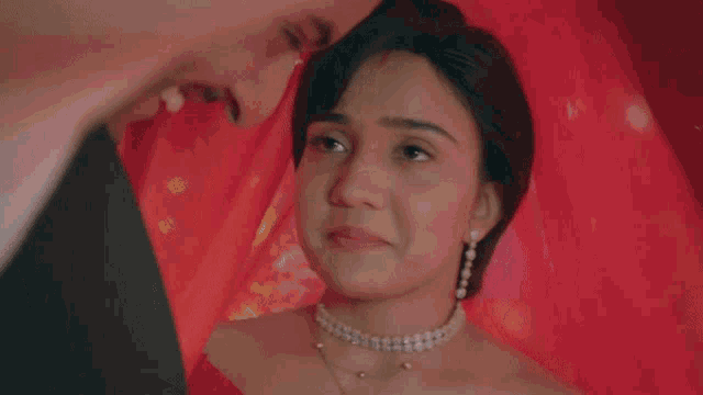 a man in a tuxedo and a woman in a red dress are looking at each other