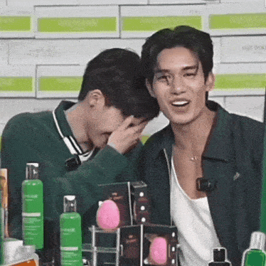 two men are standing next to each other and one of them is covering his face